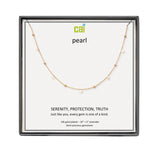 A CAI gold-plated pearl necklace with a delicate chain and small spaced pearls, presented in a square black gift box on a white backing card. The card features the brand logo 'cai' and the word 'pearl' along with product details. Available at Be Charmed