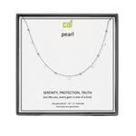 A CAI silver necklace with tiny pearl-like beads and small clear gemstones, displayed on a white card inside a square black gift box. The card reads 'cai pearl' and 'SERENITY, PROTECTION, TRUTH'. Available at Be Charmed