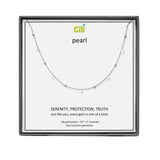 A CAI silver necklace with tiny pearl-like beads and small clear gemstones, displayed on a white card inside a square black gift box. The card reads 'cai pearl' and 'SERENITY, PROTECTION, TRUTH'. Available at Be Charmed