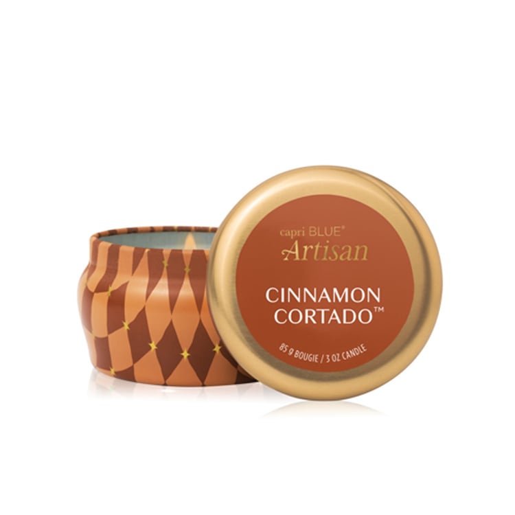 Mini Tin Candle with decorative lid labeled 'Cinnamon Cortado' by capri BLUE on a white background. Available at Be Charmed