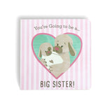 A book with a pink and white striped background featuring illustrations of two dogs and a baby, with the text 'You're Going To Be a Big Sister!' and 'Big Brother!'. Available at Be Charmed