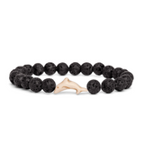 A beaded stretch Fahlo bracelet made of black porous lava stones with a small light beige dolphin charm in the center, shown on a plain white background. Available at Be Charmed