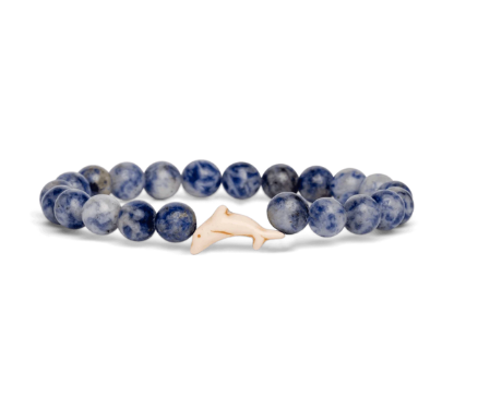 A beaded stretch Fahlo bracelet featuring round blue and white marbled beads with a small, smooth off-white dolphin charm, displayed on a clean white background. Available at Be Charmed