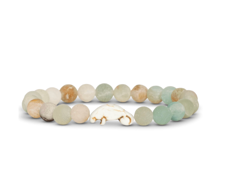 A beaded stretch Fahlo  bracelet featuring natural stone beads in soft sage green, cream, and light brown, with a manatee charm at the center, displayed on a clean white background. Available at Be Charmed