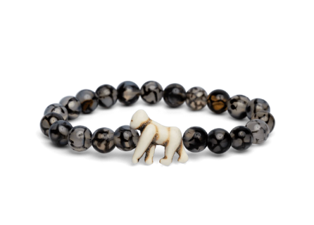 A Fahlo beaded bracelet featuring dark, marbled round beads and a small white carved gorilla charm, displayed on a clean white background. Available at Be Charmed