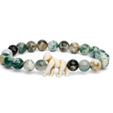 A beaded stretch Fahlo bracelet featuring round green, white, and gray marbled beads, with a small gorilla charm at the front center, displayed on a clean white background. Available at Be Charmed