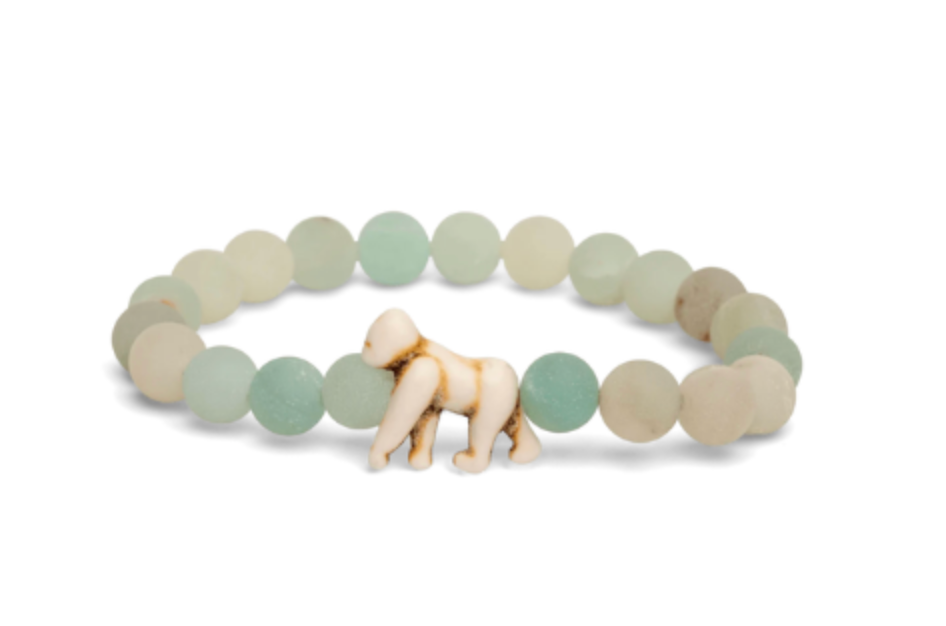 A beaded stretch Fahlo bracelet featuring matte sage green and cream stone beads, with a small carved ivory gorilla figure at the front center, set against a plain white background. Available at Be Charmed