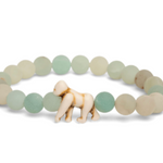 A beaded stretch Fahlo bracelet featuring matte sage green and cream stone beads, with a small carved ivory gorilla figure at the front center, set against a plain white background. Available at Be Charmed