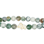 A beaded stretch Fahlo bracelet featuring round green and white marbled beads, separated by small white spacer beads, with a small white koala charm in the center, shown on a plain white background. Available at Be Charmed