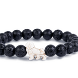 A beaded stretch Fahlo bracelet made of black porous lava stones with a small white lion charm in the center, shown on a plain white background. Available at Be Charmed