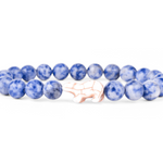 A beaded stretch Fahlo bracelet featuring round blue and white marbled beads with a central pale polar bear charm, displayed on a clean white background. Available at Be Charmed