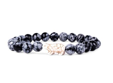 A beaded stretch fahlo bracelet featuring round black and white marbled beads with a central light beige polar bear charm, displayed on a clean white background. Available at Be Charmed