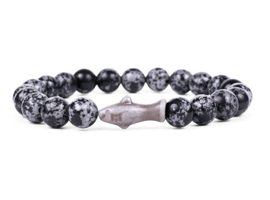 A beaded stretch Fahlo bracelet featuring round black and white speckled beads with a central shark charm, displayed on a clean white background. Available at Be Charmed