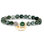 A beaded stretch Fahlo bracelet featuring dark green and white marbled beads, a single smooth green bead, and a small carved cream-colored sloth charm, displayed on a clean white background. Available at Be Charmed