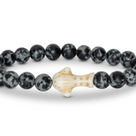 A beaded stretch Fahlo bracelet featuring round black and white mottled beads with a central off-white whale shark, shown on a plain white background. Available at Be Charmed