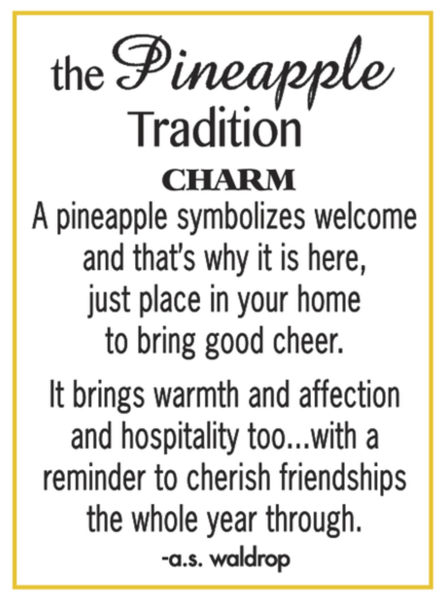 A white card with a thin yellow border, featuring black text that reads 'the Pineapple Tradition CHARM' and a quote about pineapple symbolism and warmth, signed '-a.s. Available at Be Charmed