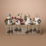 Four Christmas-themed resin figurines sitting on a weathered wooden block against a solid beige background. The set includes two snowmen and two Santa Claus figures, each with painted white bodies, colorful scarves and hats, and dark brown boots. Availabe at Be Charmed