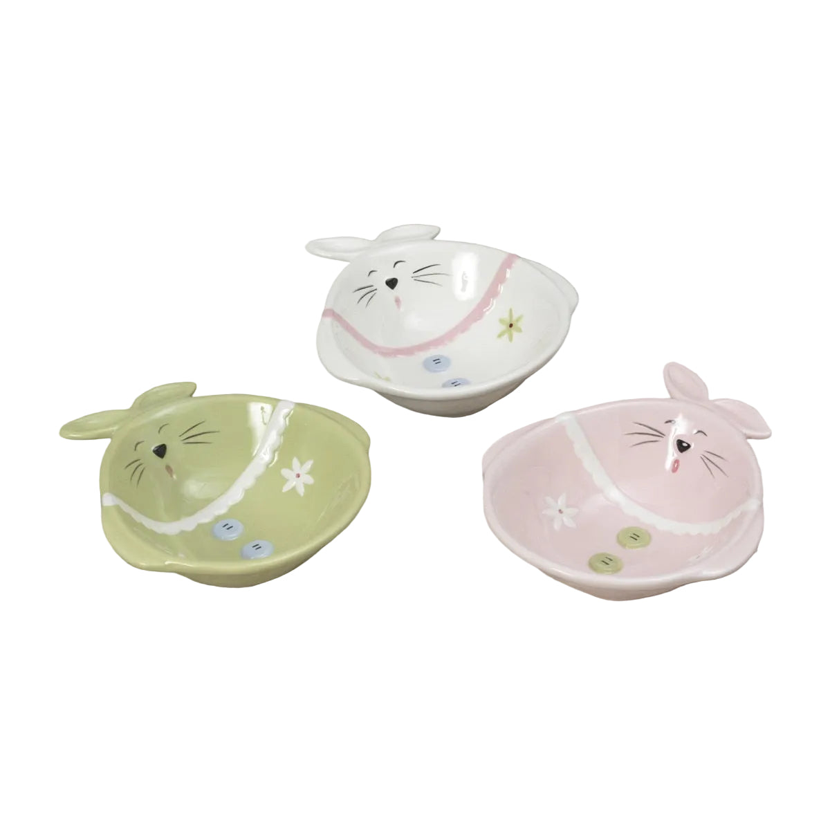 Three small bunny-shaped bowls in pastel green, white, and pink, decorated with cute faces, flowers, and buttons, arranged on a light wood surface. Available at Be Charmed
