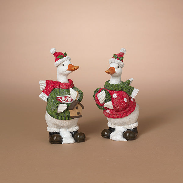 Two decorative duckf igurines dressed in holiday sweaters and Santa hats, standing side by side on a plain beige studio background. Available at Be Charmed