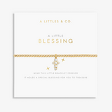 A gold chain bracelet with a small cross charm and clear stones, displayed on a white branded card that reads 'A LITTLES & CO. A LITTLE BLESSING'. Available at Be Charmed