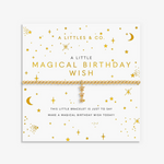 A gold celestial-themed bracelet by A Littles & Co. displayed on its white backing card, which features gold stars, moons, and text reading 'A LITTLE MAGICAL BIRTHDAY WISH'. Available at Be Charmed