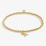 A Littles & Co Christmas Cardinal gold bracelet featuring a delicate cardinal charm on a beaded band, available at Be Charmed