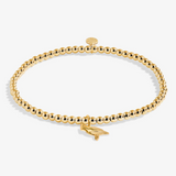 A Littles & Co Christmas Cardinal gold bracelet featuring a delicate cardinal charm on a beaded band, available at Be Charmed