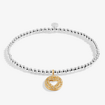 A silver beaded bracelet with a gold double-heart charm paved with small clear stones. Available at Be Charmed