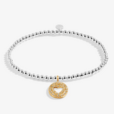 A silver beaded bracelet with a gold double-heart charm paved with small clear stones. Available at Be Charmed