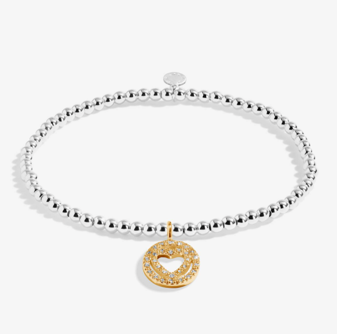 A silver beaded bracelet with a gold double-heart charm paved with small clear stones. Available at Be Charmed