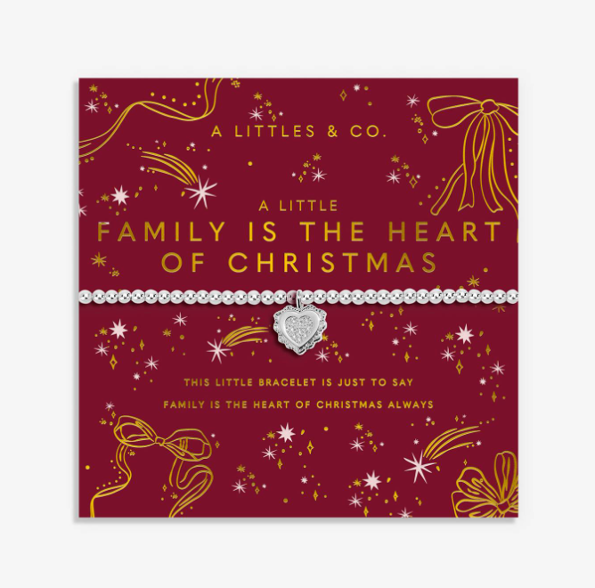 A silver heart-shaped charm bracelet by A Littles & Co. displayed on its red and gold Christmas-themed gift card, which reads 'A LITTLE FAMILY IS THE HEART OF CHRISTMAS'. Available at Be charmed
