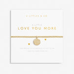 A gold-tone plated bracelet with a stretch design and a coin charm, packaged in a white card with the text 'A Littles & Co. just to say, I love you more every day. Available at Be Charmed