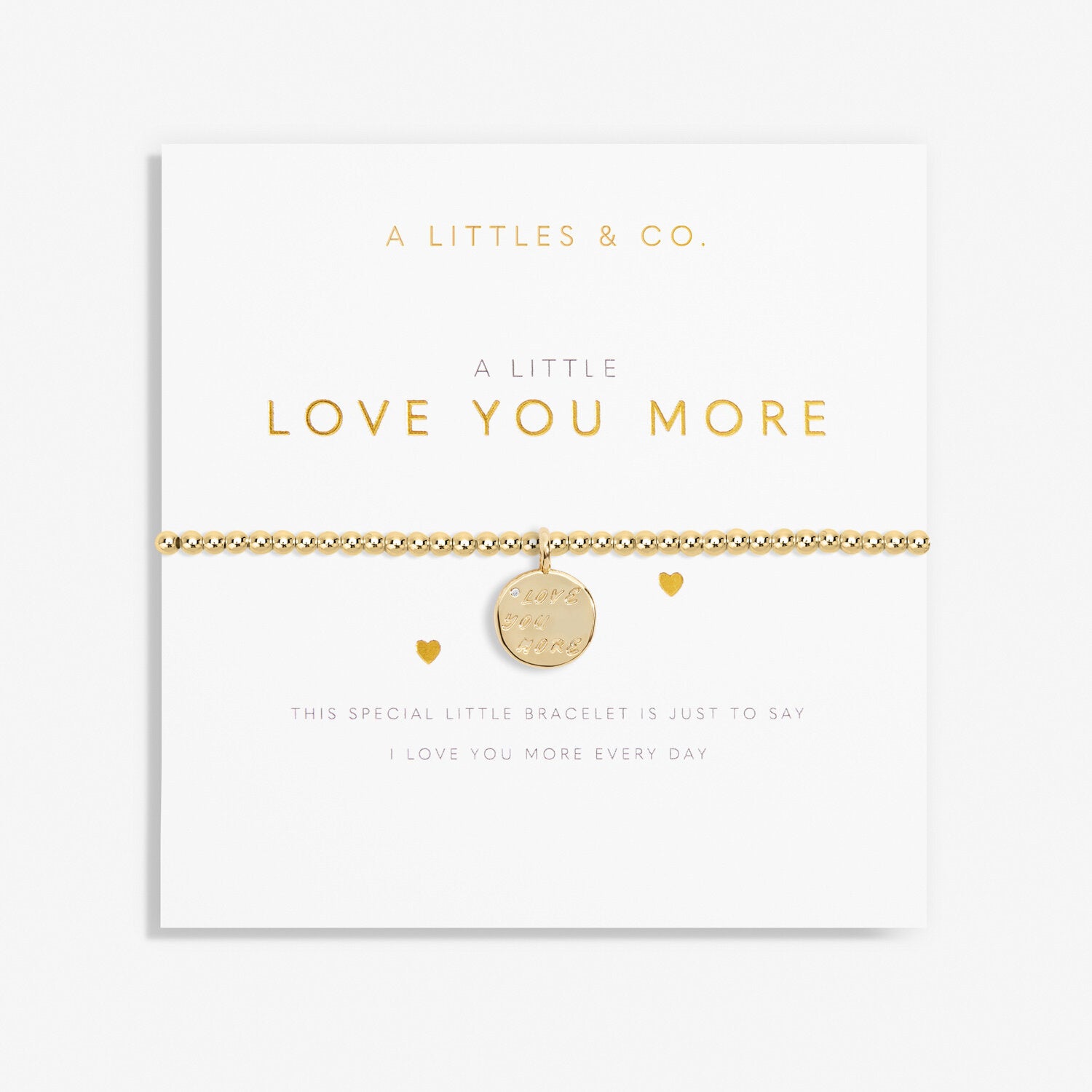 A gold-tone plated bracelet with a stretch design and a coin charm, packaged in a white card with the text 'A Littles & Co. just to say, I love you more every day. Available at Be Charmed