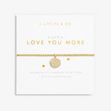 A gold-tone plated bracelet with a stretch design and a coin charm, packaged in a white card with the text 'A Littles & Co. just to say, I love you more every day. Available at Be Charmed