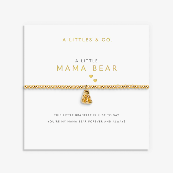 A gold chain bracelet with a small teddy bear charm and two heart charms, displayed on a white card from A Littles & Co. The card reads 'A LITTLE MAMA BEAR' and includes a sentimental message at the bottom. Available at Be Charmed