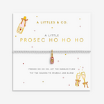 A silver-toned bracelet with a pink and gold 'Prosecco' pendant, displayed on a white branded card from 'A Littles & Co.' with champagne bottle and glasses illustrations. Available at Be Charmed