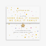 A silver charm bracelet with a gold star charm displayed on a white gift card. The card features gold and black text, and is decorated with small scattered stars in gold, pink, blue, and green. Available at Be Charmed