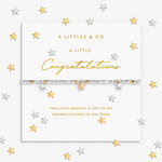 A silver and gold beaded bracelet with star charms, presented on a white card from A Littles & Co. with gold and silver star confetti scattered around the background. Available at Be Charmed