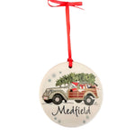 A round ceramic ornament featuring a depiction of Santa Claus in a woodie vehicle with the text 'MEDFIELD' on the side, hanging from a red ribbon. Available at Be Charmed