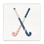 Square block sign featuring two crossed field hockey sticks on a distressed white wood background. One stick is navy blue with a white wrapped handle, and the other is pink and white striped with a navy handle. Availble at Be Charmed
