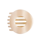 A Teletioes Almond Beige hair claw clip with a circular design and a central cutout, shown on a solid off-white background. Available at Be Charmed