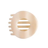 A Teletioes Almond Beige hair claw clip with a circular design and a central cutout, shown on a solid off-white background. Available at Be Charmed
