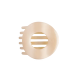 A Teleties almond beige  plastic hair claw clip with a circular design and three side teeth, shown on a solid off-white background. Available at Be Charmed