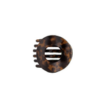 A circular hair claw clip in a classic tortoiseshell pattern, featuring a central ventilation slot and five outer teeth, shown on a plain white background. Available at Be Charmed