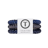 Three Teleties hair stretch bands in navy blue and clear patterned material, wrapped around a white paper band with the Teleties logo and name. Avaialbe at Be Chamred