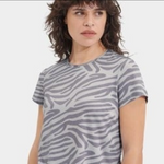Person wearing a gray zebra pattern t-shirt on a white background. Available at be Charmed