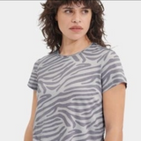 Person wearing a gray zebra pattern t-shirt on a white background. Available at be Charmed