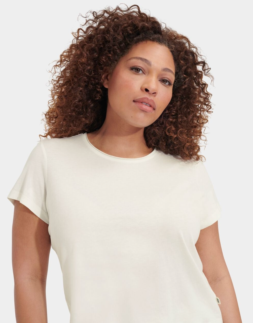 Woman wearing a white t-shirt against a plain background. Available at Be Charmed