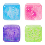 Four colorful glittery cubes in blue, pink, purple, and green on a white background. Available at Be Charmed