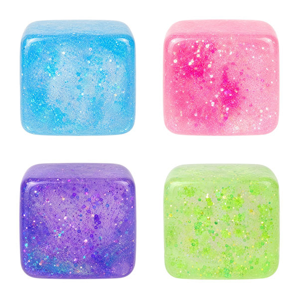 Four colorful glittery cubes in blue, pink, purple, and green on a white background. Available at Be Charmed